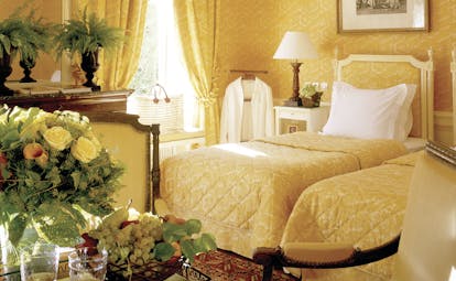 Bedroom decorated with a yellow colour scheme, two single beds and flowers arranged on a table
