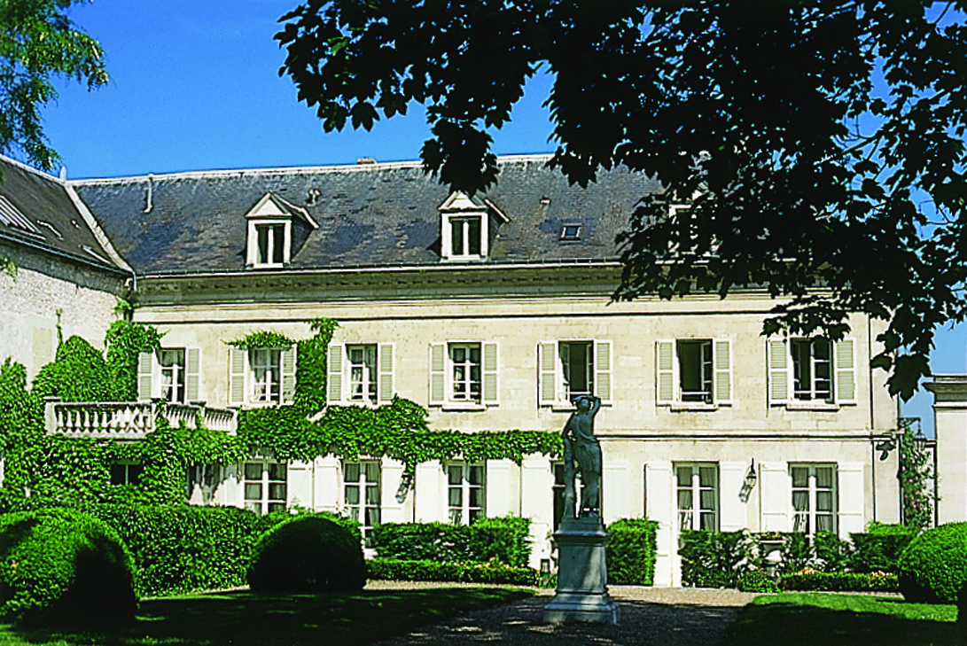 Exterior of hotel, a large stone building with green vines growing up hotel 