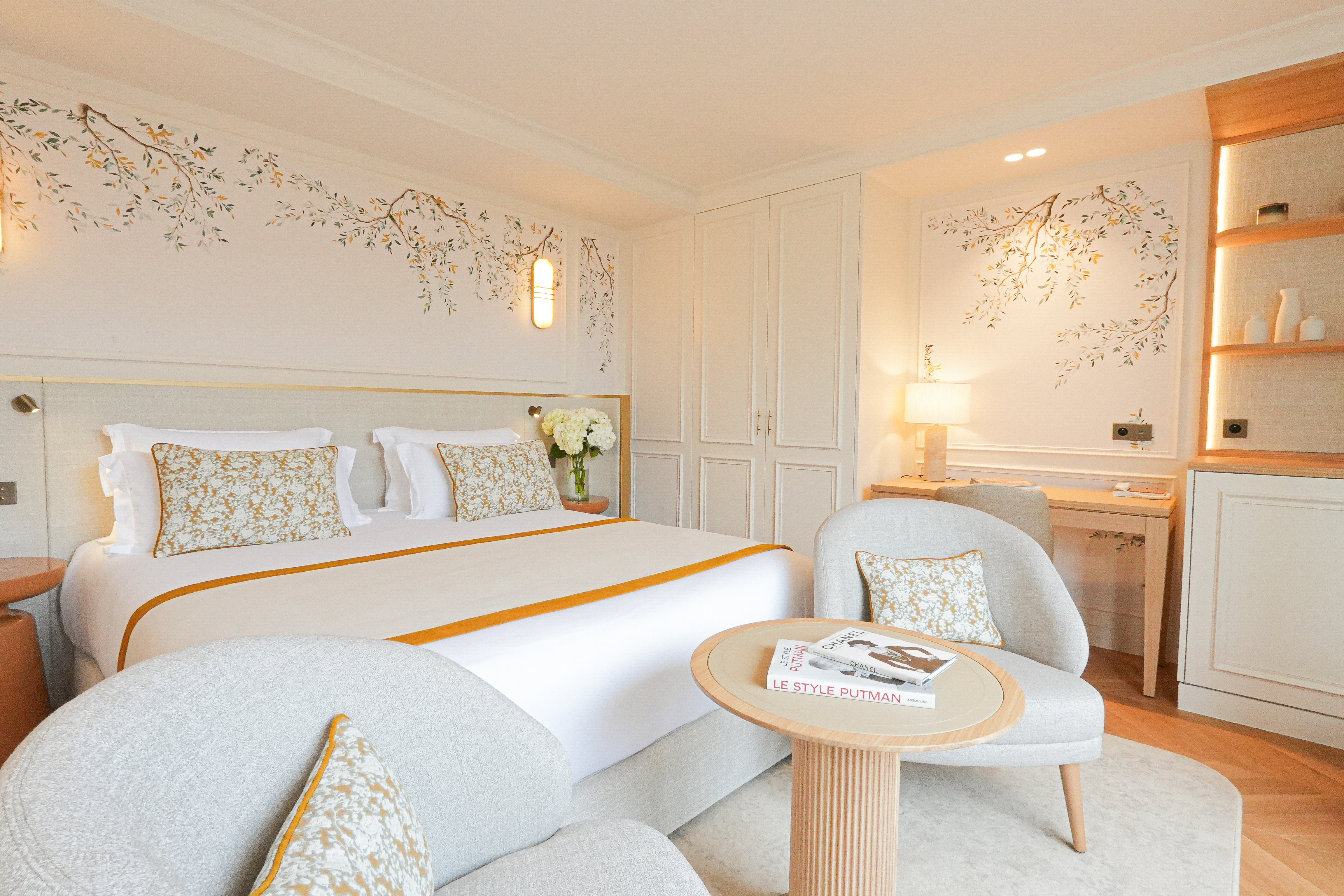 Relais d'Amboise room with neutral colour palette with pops of orange detailing, nature-inspired elements in the decor, two chairs, double bed, table, and tables and lamps