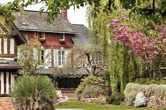 Auberge de la Source Normandy outdoor garden brick building overlooking trees with pink blossom and bushes