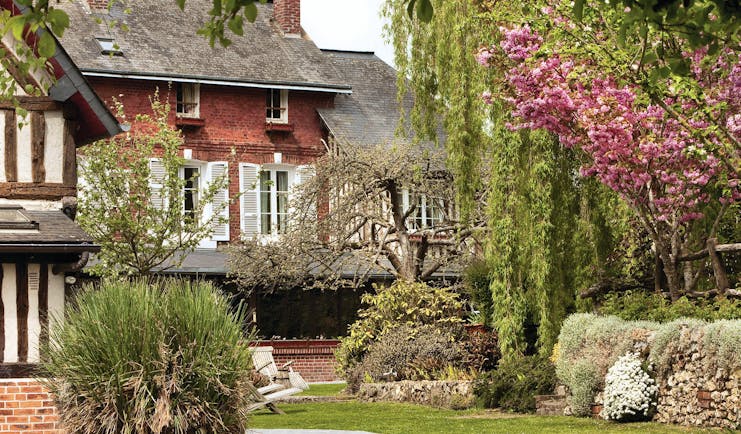 Auberge de la Source Normandy outdoor garden brick building overlooking trees with pink blossom and bushes
