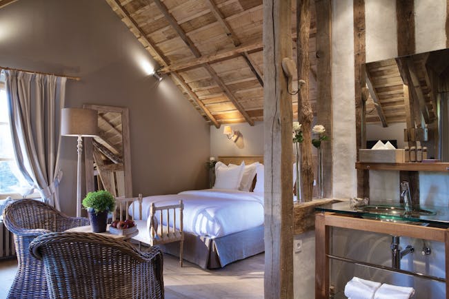 Auberge de la Source Normandy superior room with wooden roof exposed beams wicker chairs and a glass sink area
