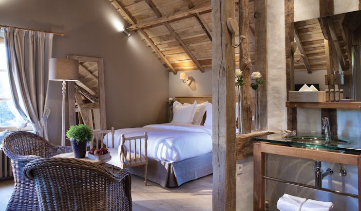 Auberge de la Source Normandy superior room with wooden roof exposed beams wicker chairs and a glass sink area