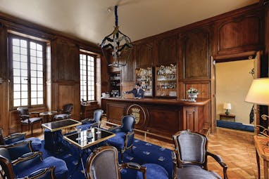 Bar at the Chateau d'Audrieu with wood pannelled walls, blue chairs and a blue rug