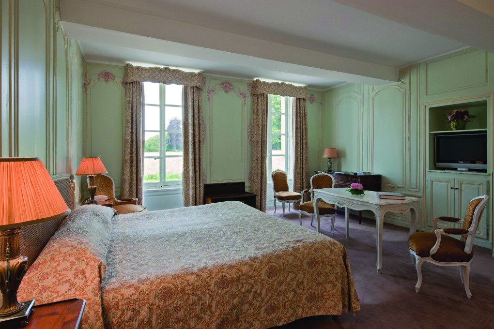 Bedroom at the Chateau d'Audrieu with a blue and gold colour scheme, large oduble bed and lamp