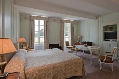 Bedroom at the Chateau d'Audrieu with a blue and gold colour scheme, large oduble bed and lamp