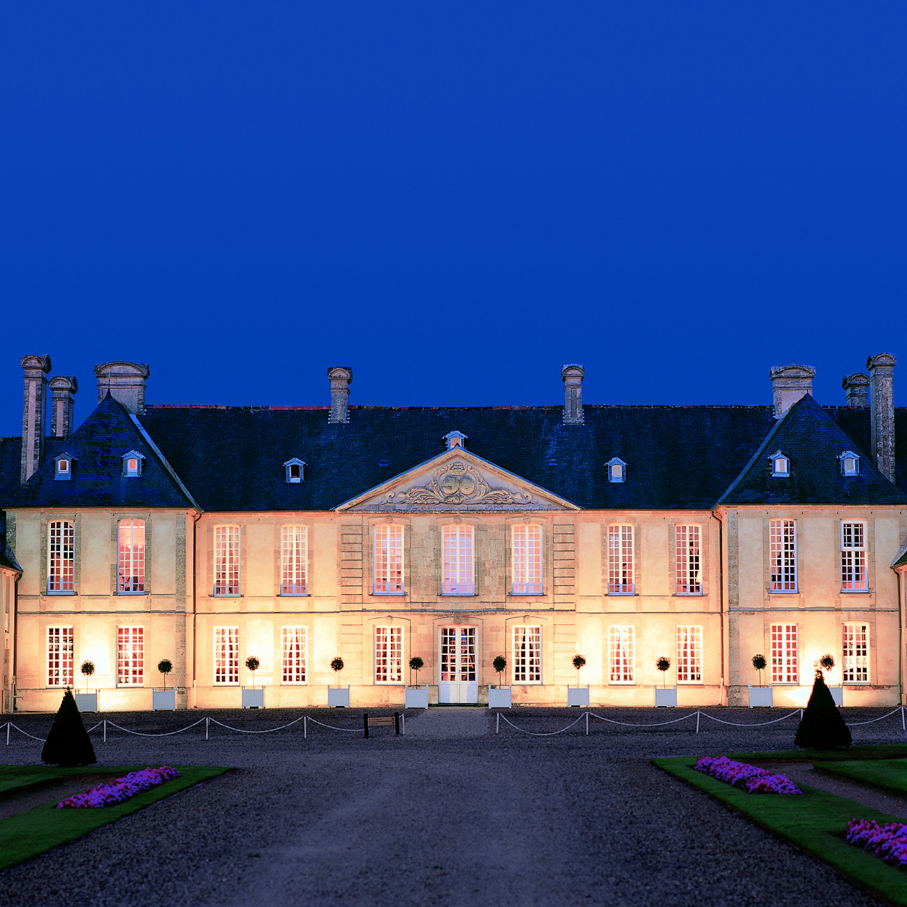 Exterior of the Chateau d'Audrieu, shows big white hotel building lit up with yellow lights 