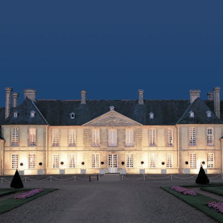 Exterior of the Chateau d'Audrieu, shows big white hotel building lit up with yellow lights 