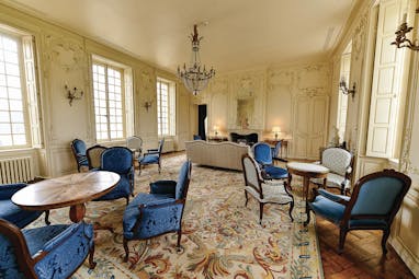Lounge at the Chateau d'Audrieu with wooden tables and blue chairs set up around the room