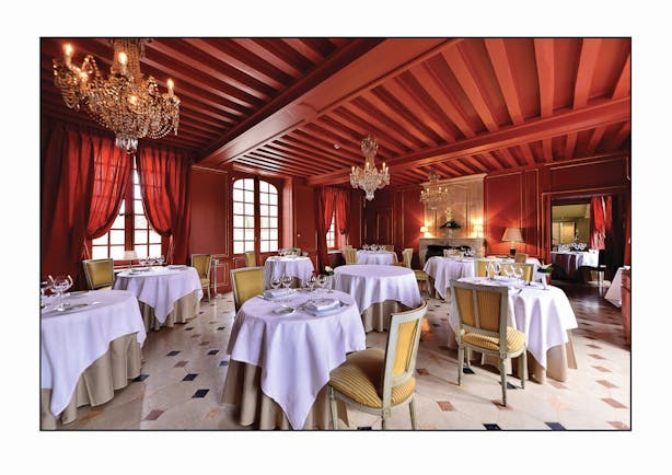 Chateau d'Audrieu dining area with red ceilings and walls and dining tables set up around the room 