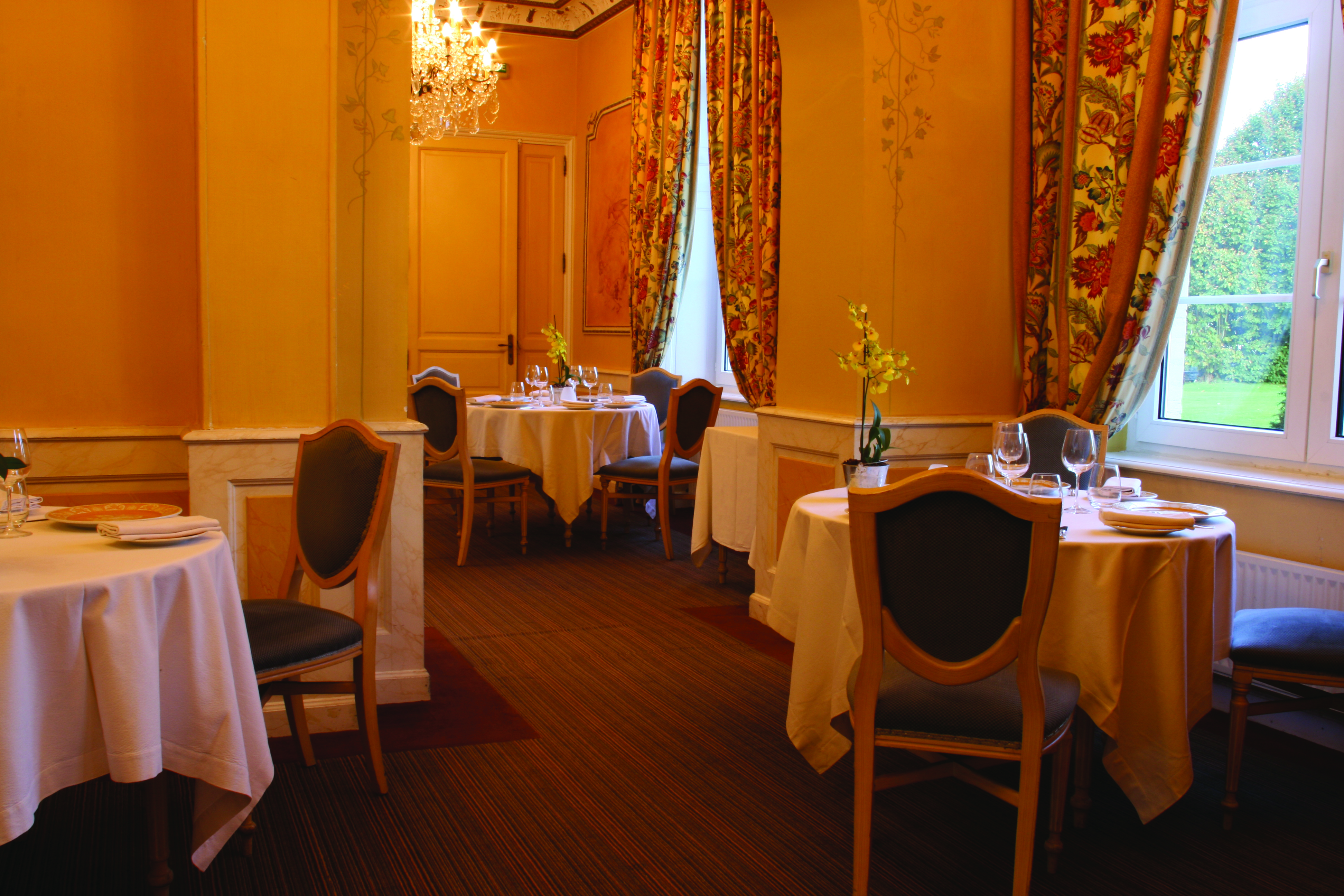 Restaurant with tables and chairs set up, lighting provided by a chandelier