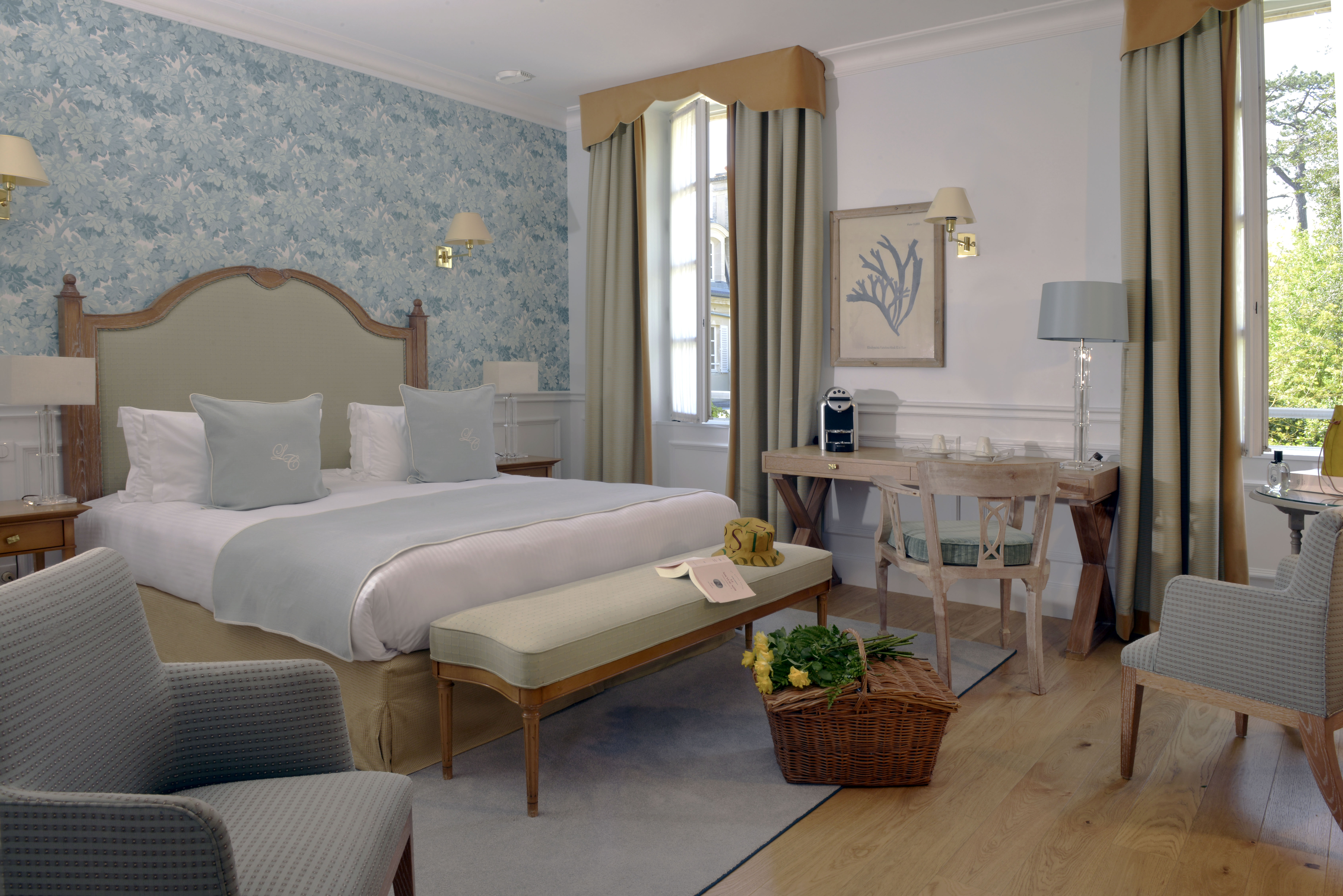 Bedroom with large double bed, curtains, arm chair and desk