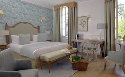 Bedroom with large double bed, curtains, arm chair and desk