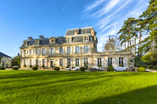 Yellow stone classical French chateau with lawns and trees Chateau la Cheneviere Normandy