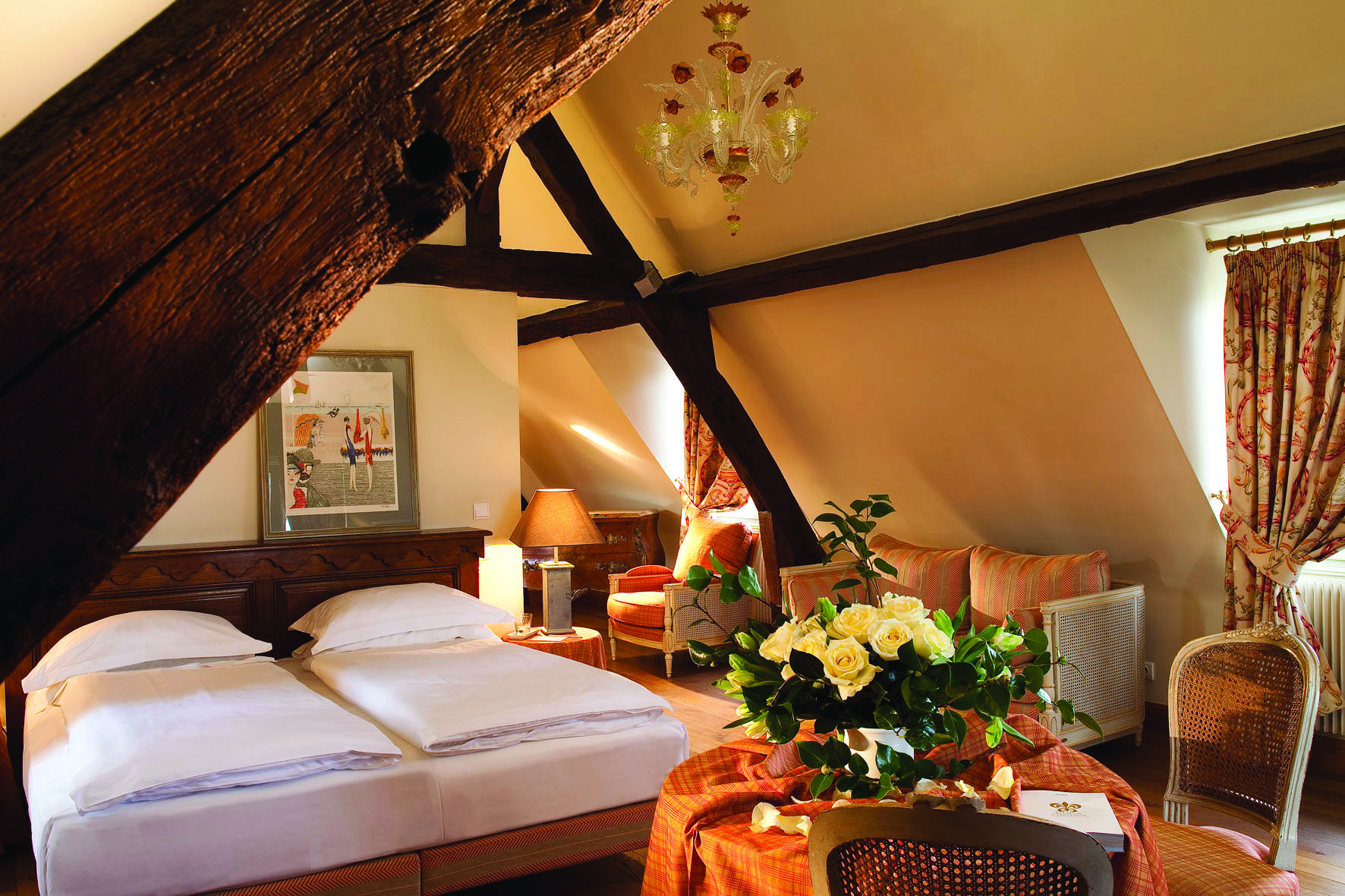 La Ferme Saint Simeon Normandy junior suite bedroom with exposed beams a sofa and table with white roses