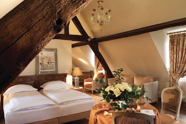La Ferme Saint Simeon Normandy junior suite bedroom with exposed beams a sofa and table with white roses