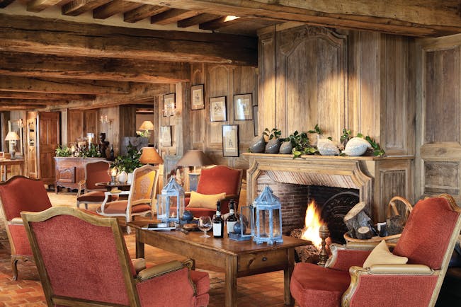 La Ferme Saint Simeon Normandy lounge area with wooden walls exposed beam and a fireplace