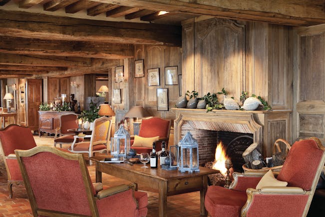 La Ferme Saint Simeon Normandy lounge area with wooden walls exposed beam and a fireplace