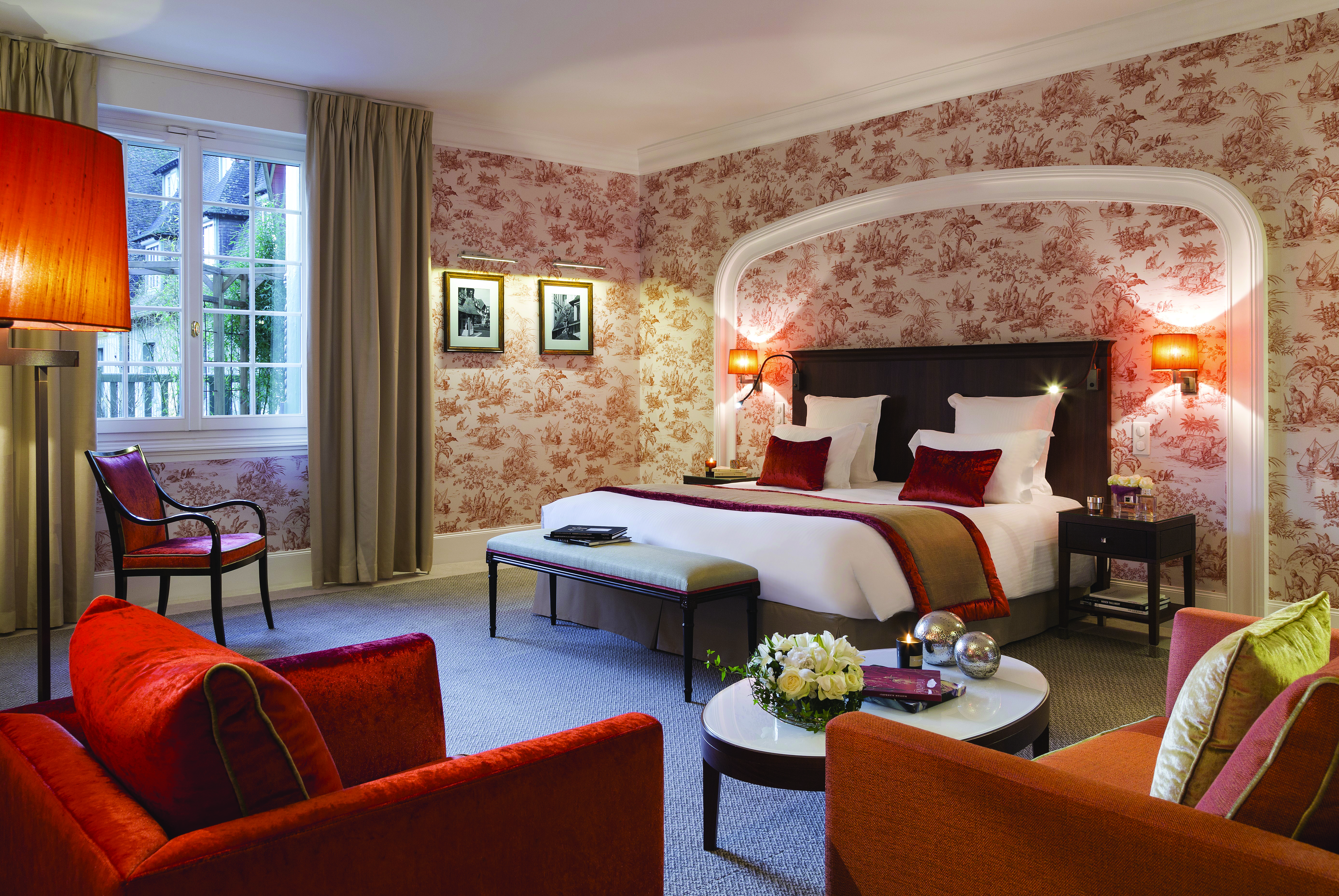 Bedroom at the Hotel Barriere with double bed, arm chairs and flower arrangements