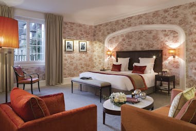 Bedroom at the Hotel Barriere with double bed, arm chairs and flower arrangements