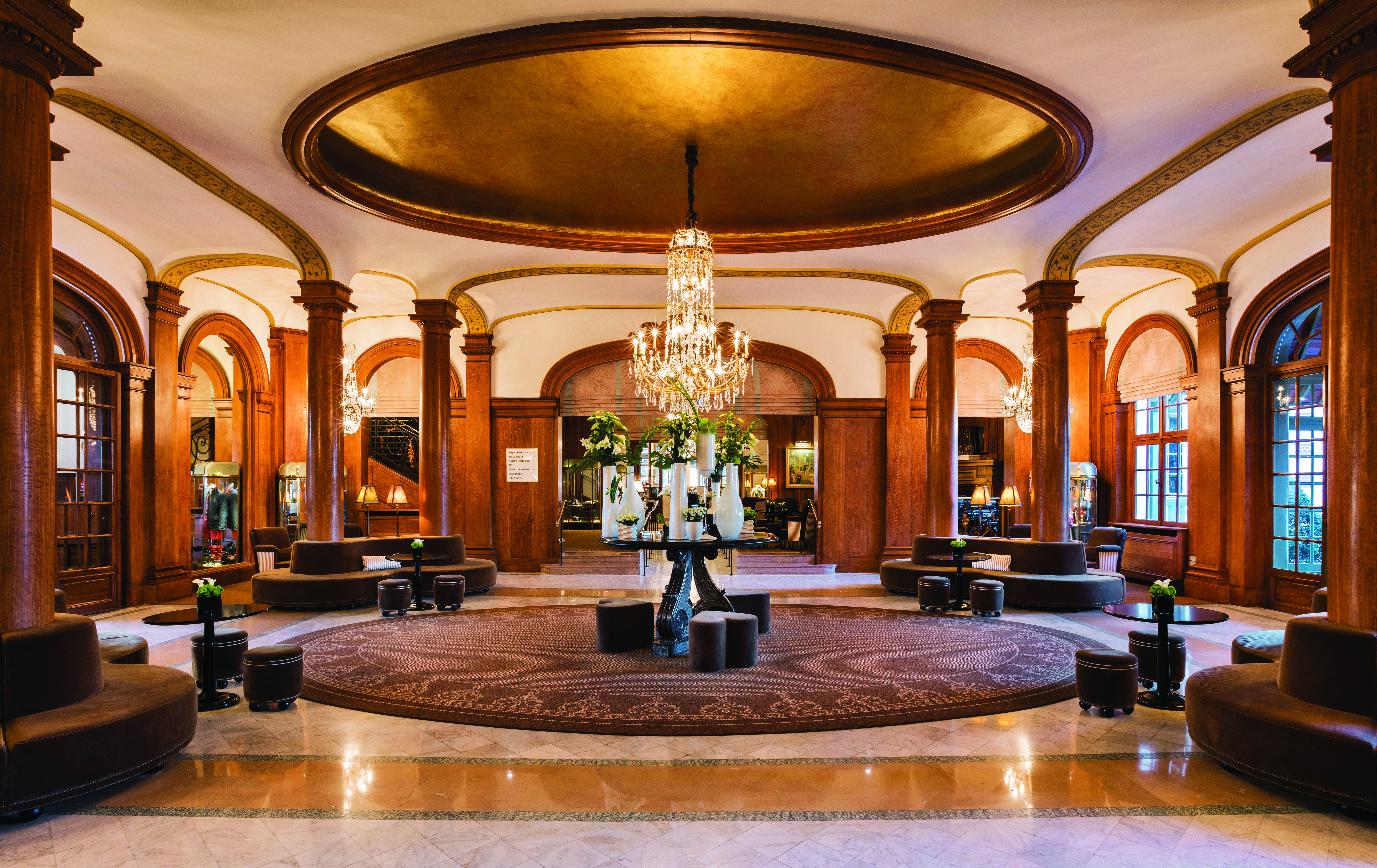 Reception area with wooden pillars, a large chandelier and lots of padded seating areas