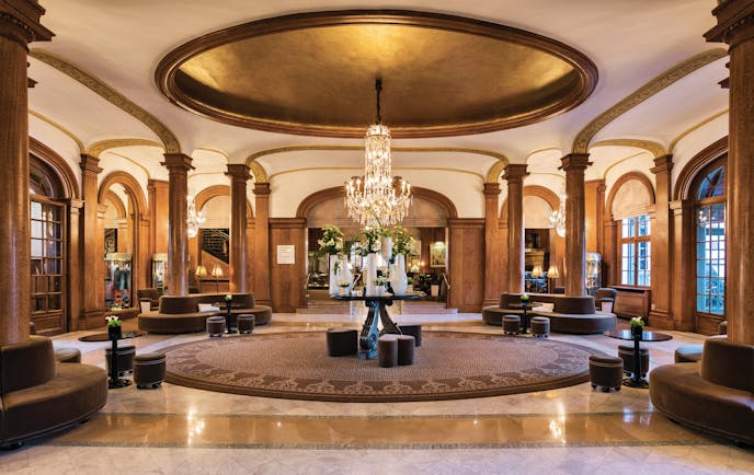 Reception area with wooden pillars, a large chandelier and lots of padded seating areas