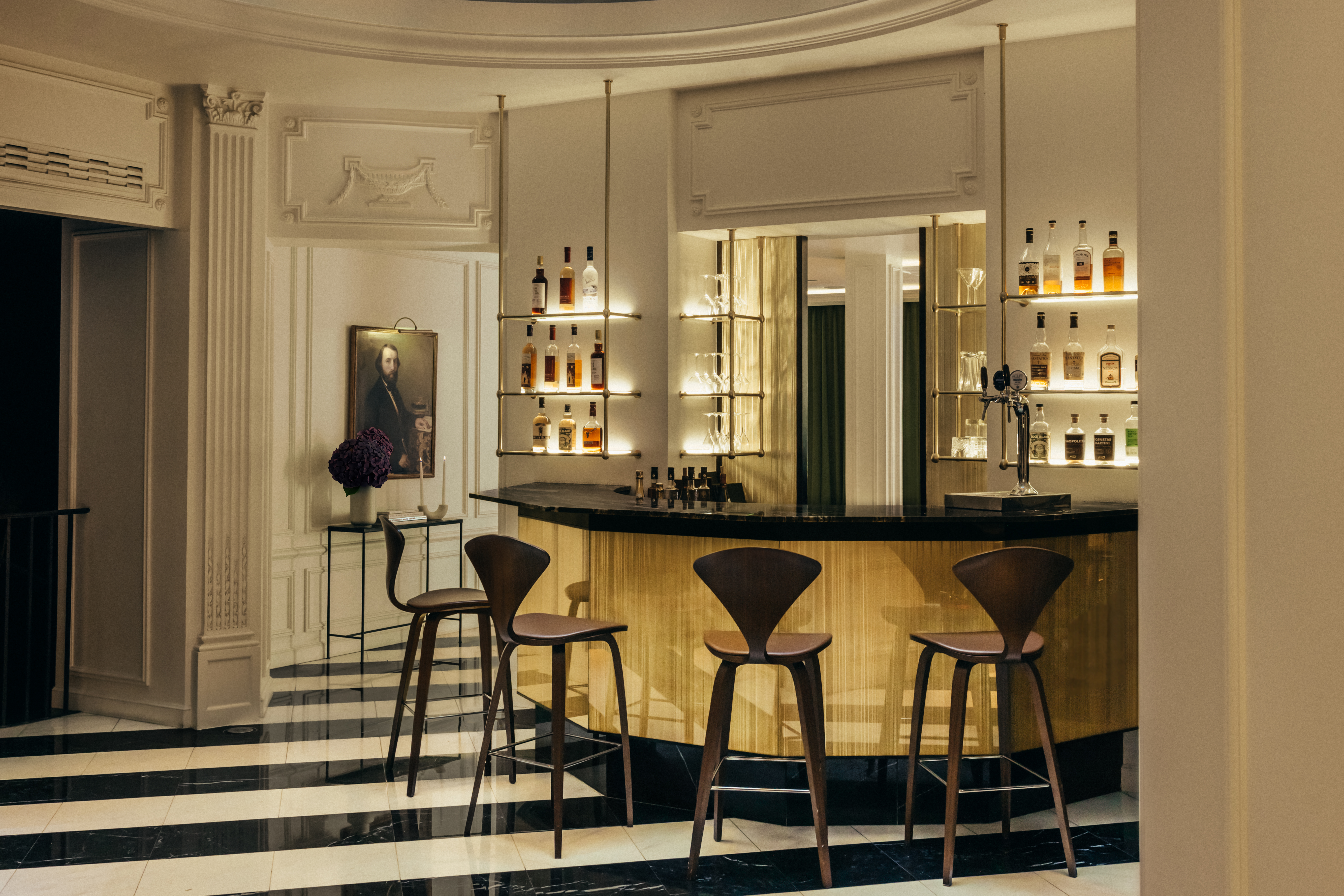 Hotel Bourgogne et Montana bar, with gold and cream styling, black and white striped marble floor, and lit shelves of spirit bottles behind the curved bar