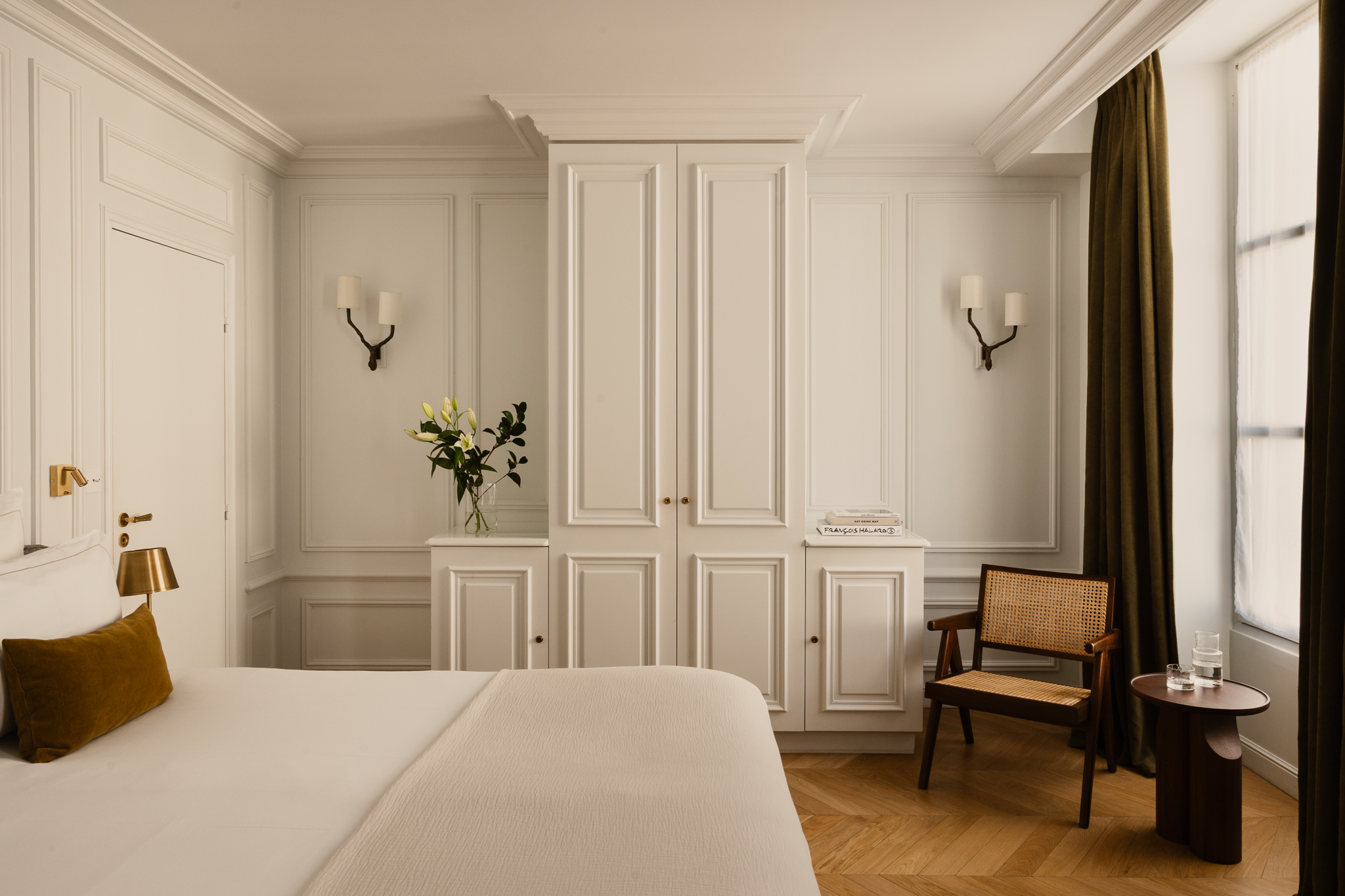 Hotel Bourgogne et Montana Deluxe Room with white panelled walls, tall windows, wooden floor, double bed, gold lamps and light fixings