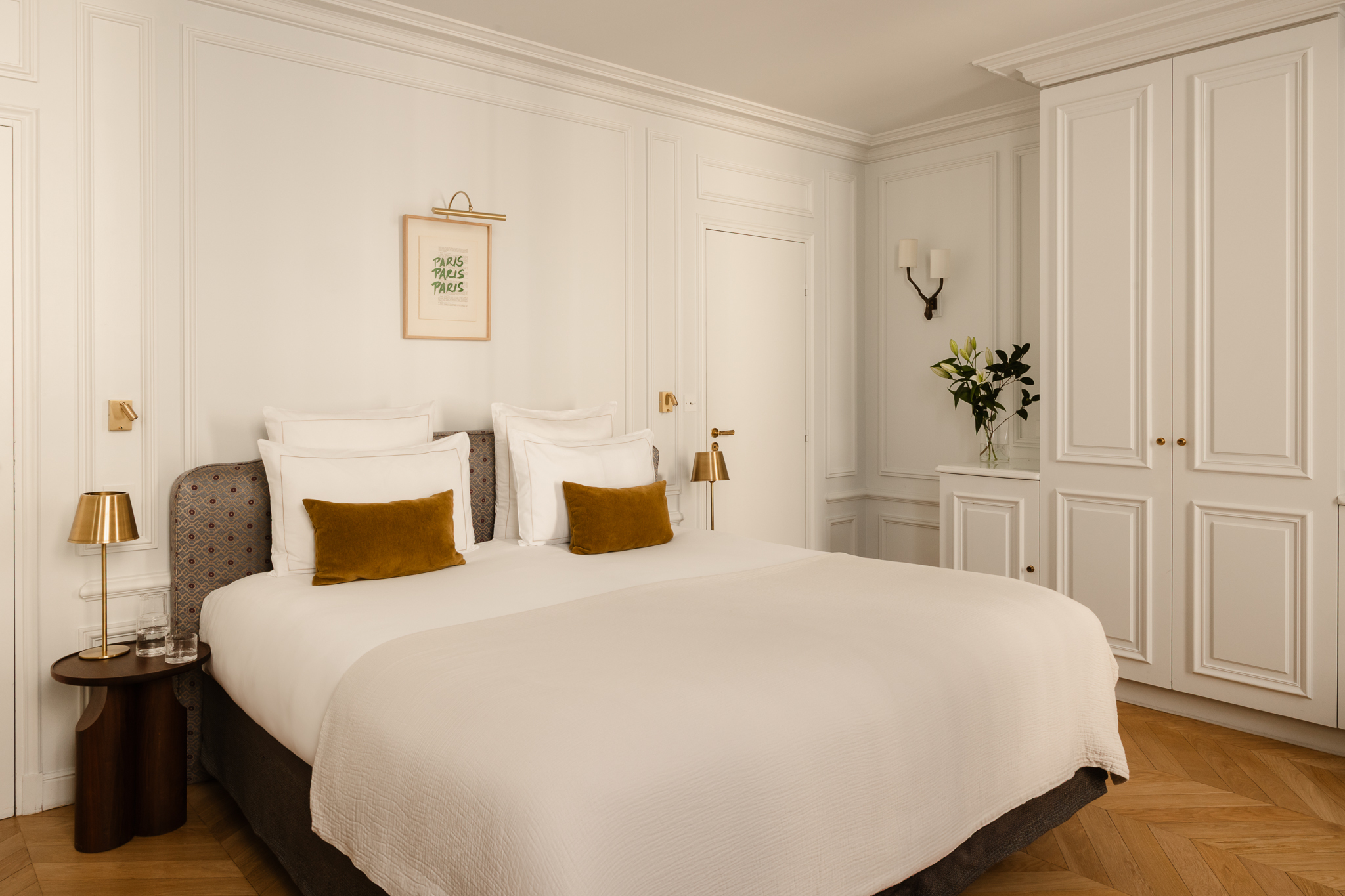 Hotel Bourgogne et Montana Deluxe Room with double bed, gold cushions, wooden floor, white panelled walls, and gold lamps