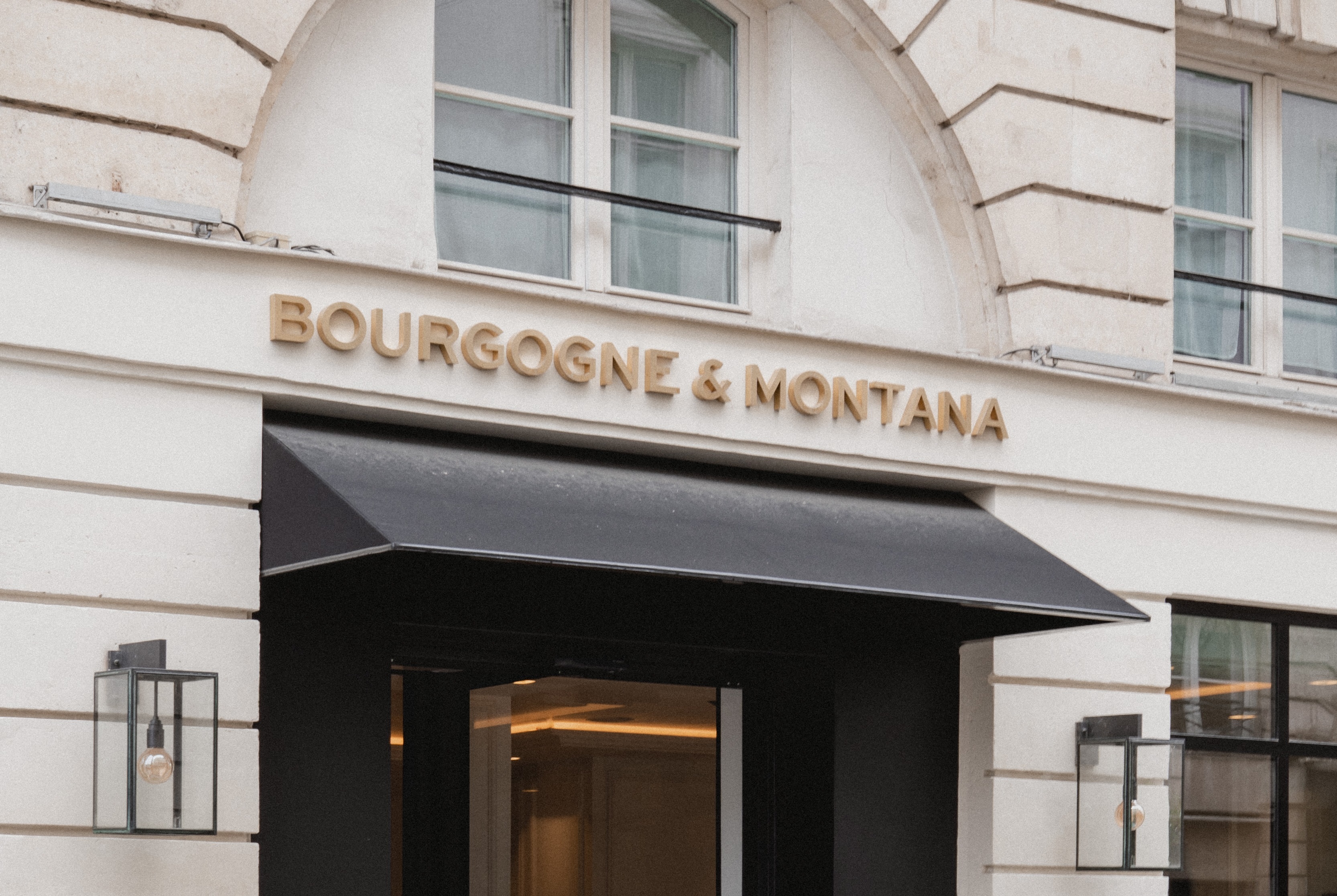 Hotel Bourgogne et Montana exterior with gold lettering above a black awning against the light stone walls