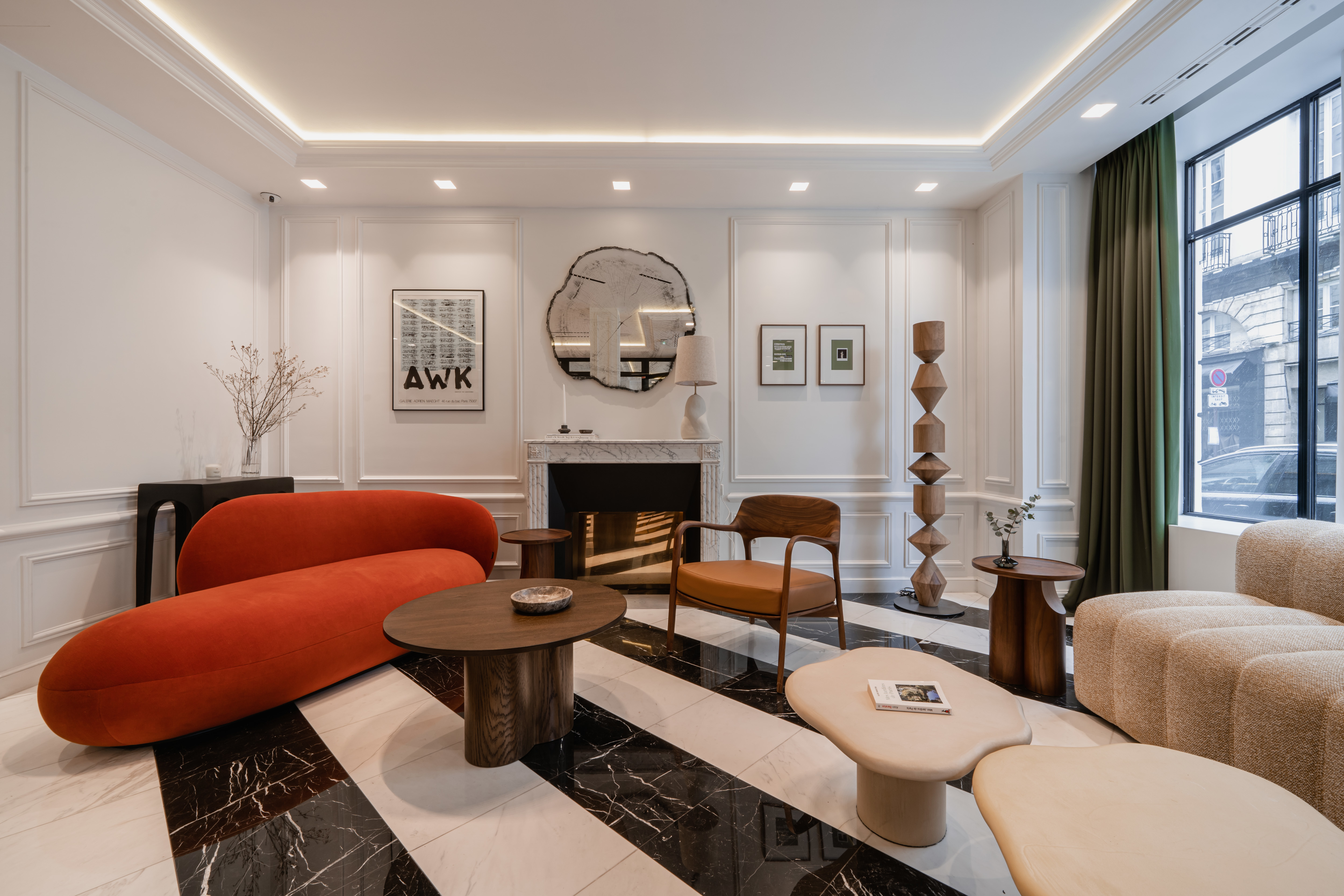 Hotel Bourgogne et Montana Lobby with black and white striped marble floor, panelled white walls, large street-facing windows, and artistic furnishings, including a deep orange chaise longue
