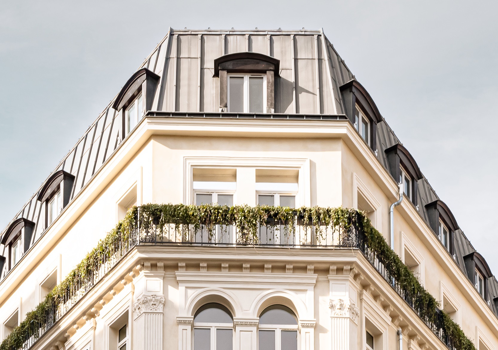 Chateau des Fleurs townhouse exterior with white stone walls, grey roof, arched windows, and flower boxes on juliet balconies