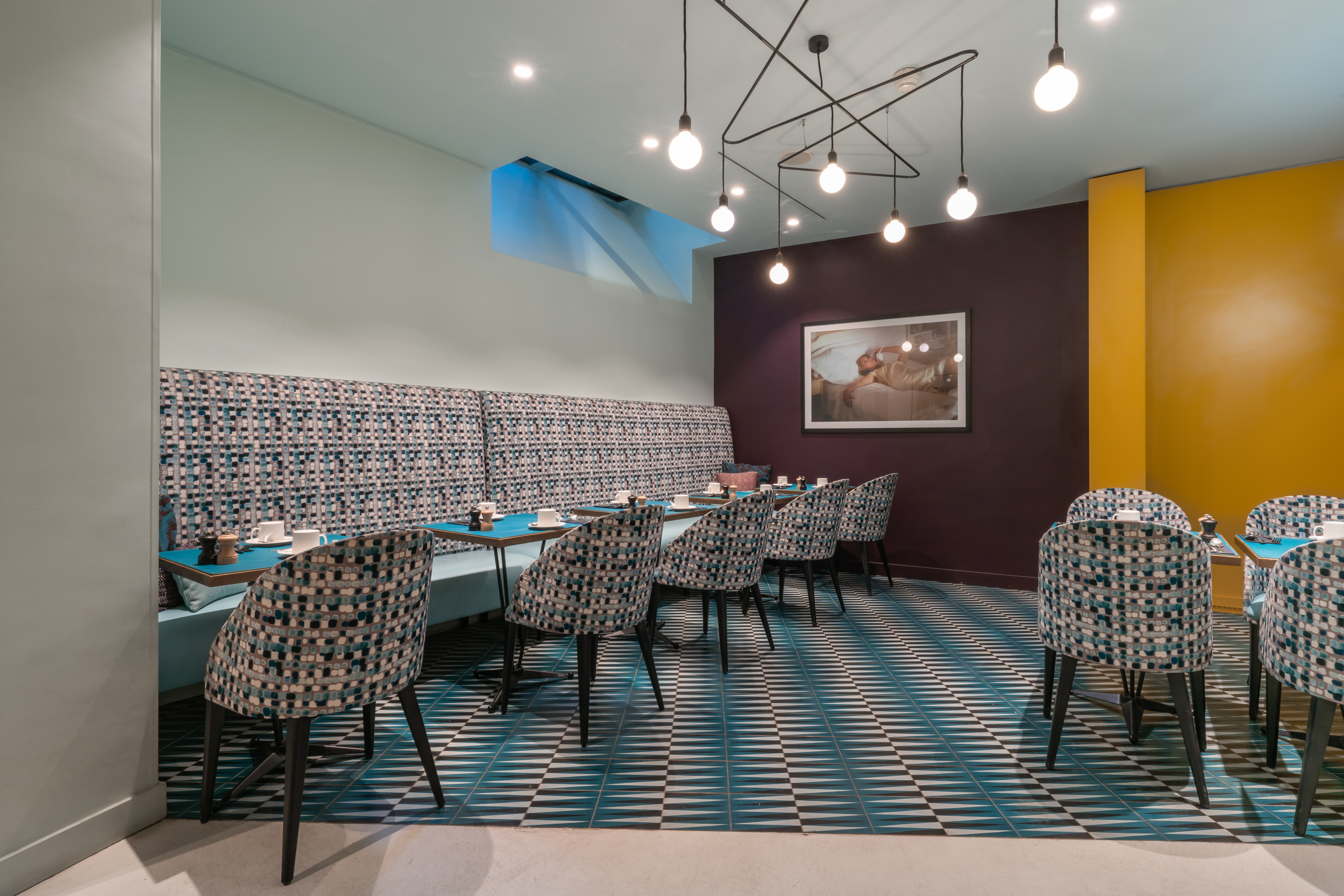 Hotel Artus breakfast cellar, with patterned grey and blue furnishings and floor tiles, and an arty 1950s-inspired style