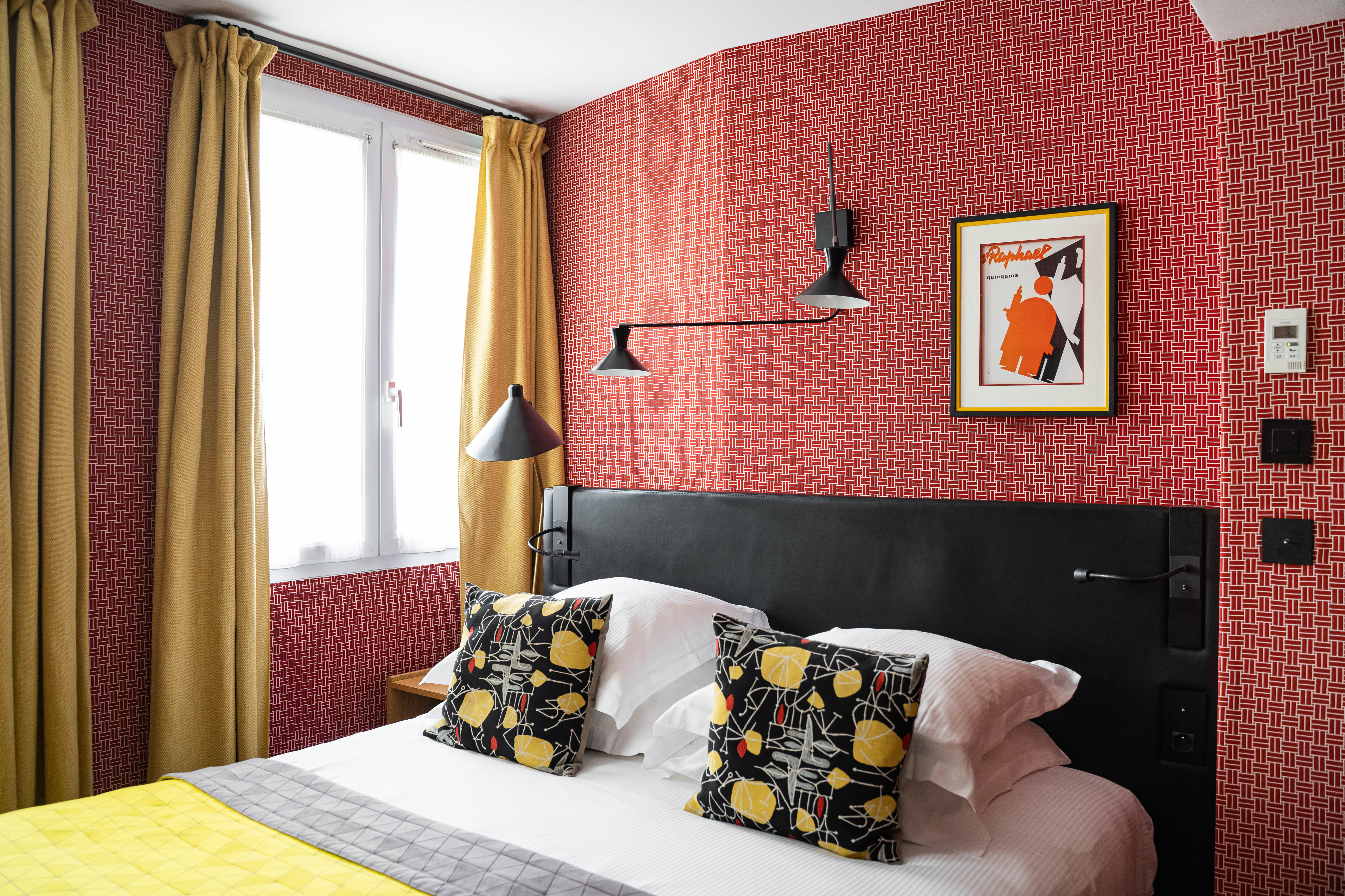 Hotel Artus Classic Room with patterned pink walls, yellow curtains and throw, and blank headboard