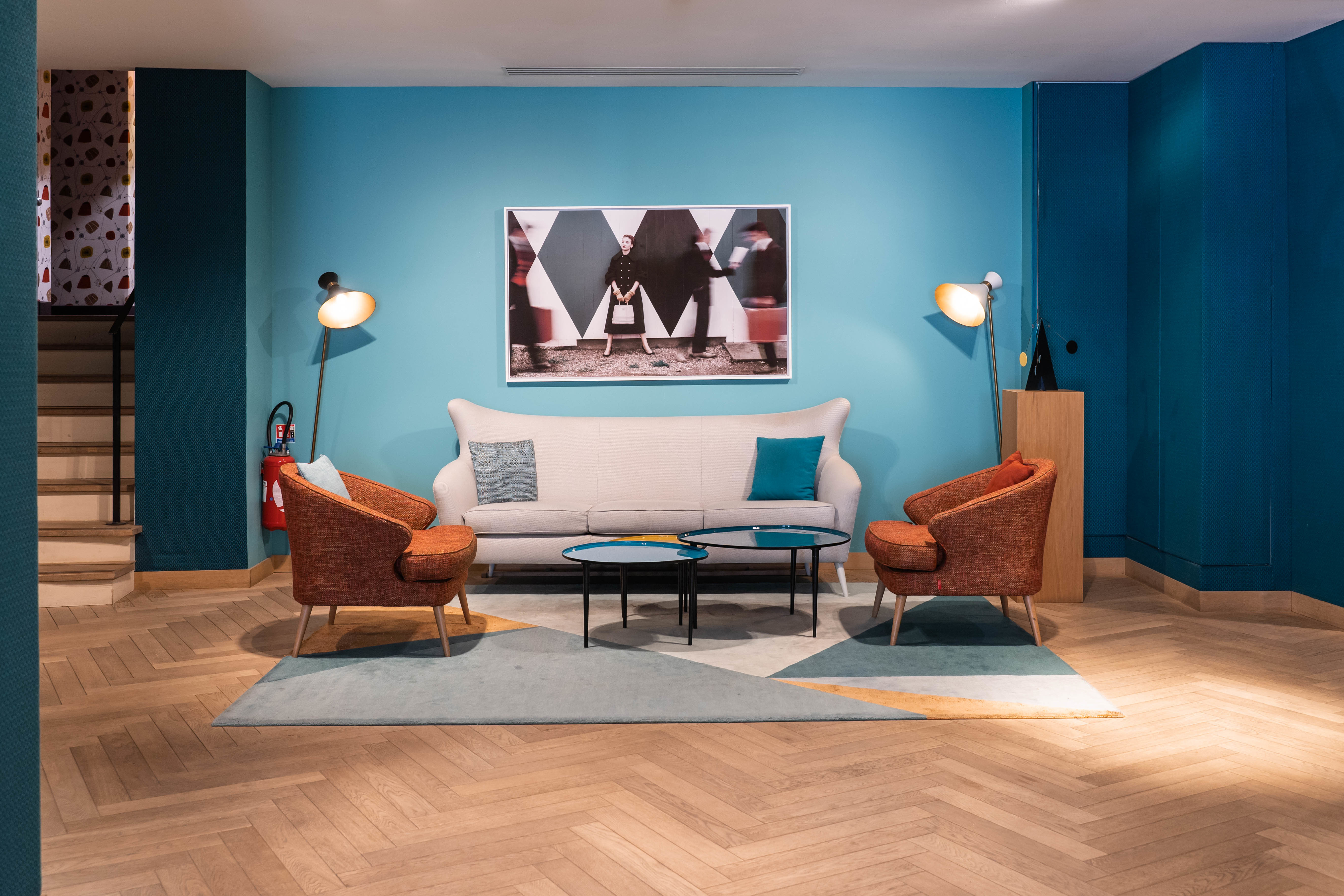 Hotel Artus lobby, with bright blue wall and statement furniture against a light wood herringbone floor