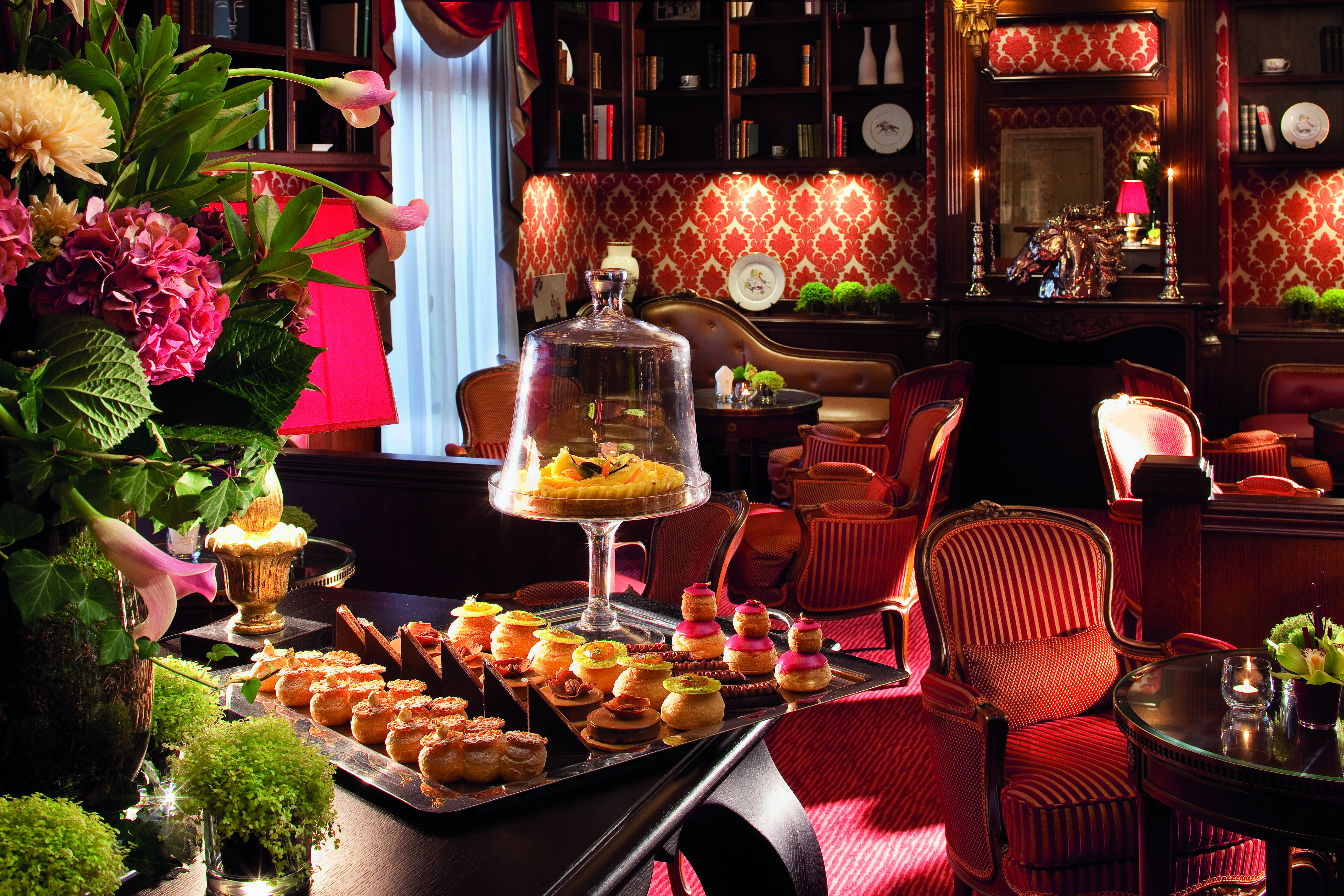 Auberge du Jeu de Paume Paris bar area with red and white wallpaper chairs and sofas tables and a table with pastries