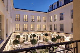 Auberge du Jeu de Paume Paris exterior courtyard with several tables and chairs overlooked by a white building