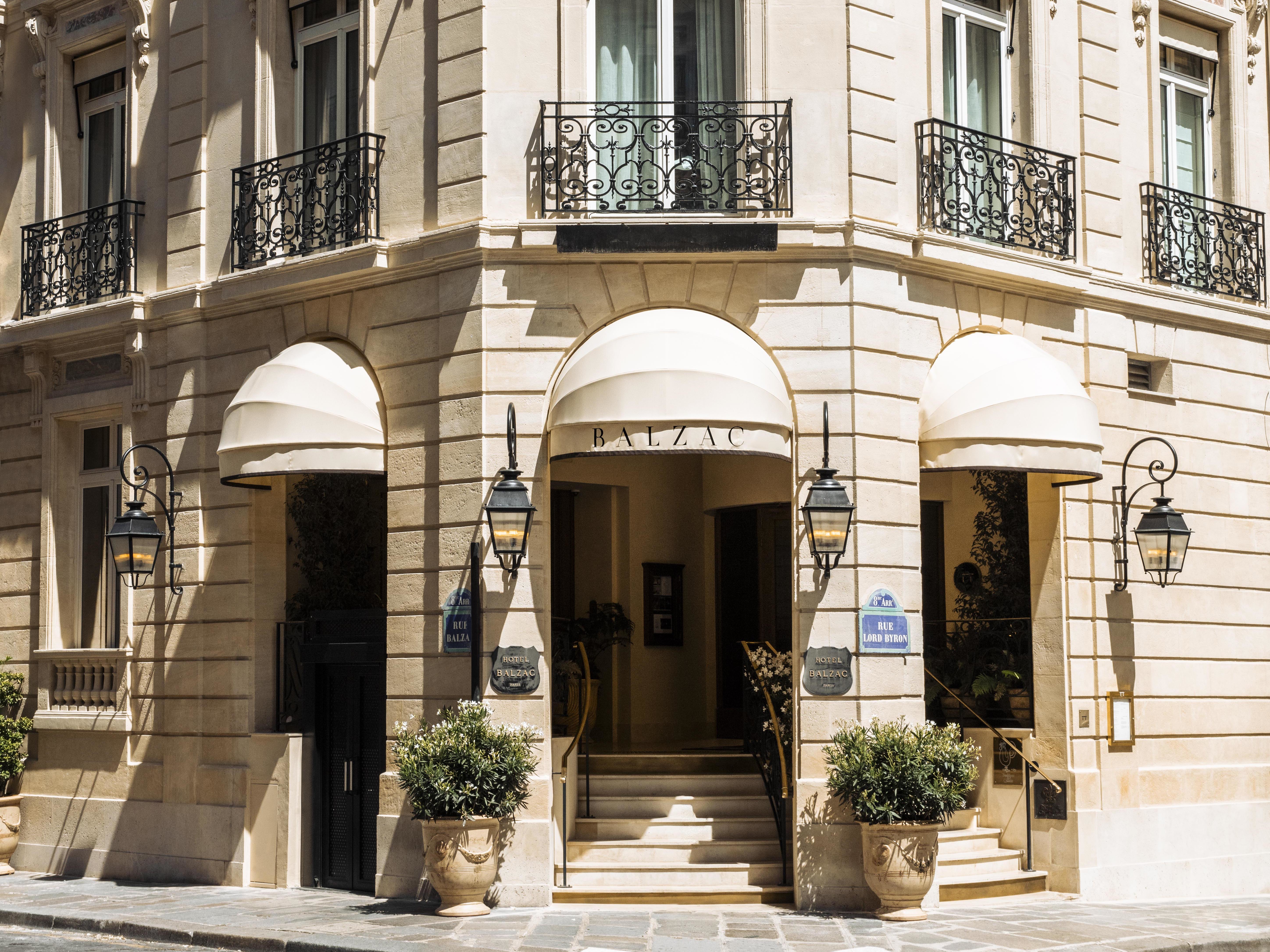 Hotel Balzac facade with stone walls, arched, canopied doors and windows, and juliet balconies on first floor windows
