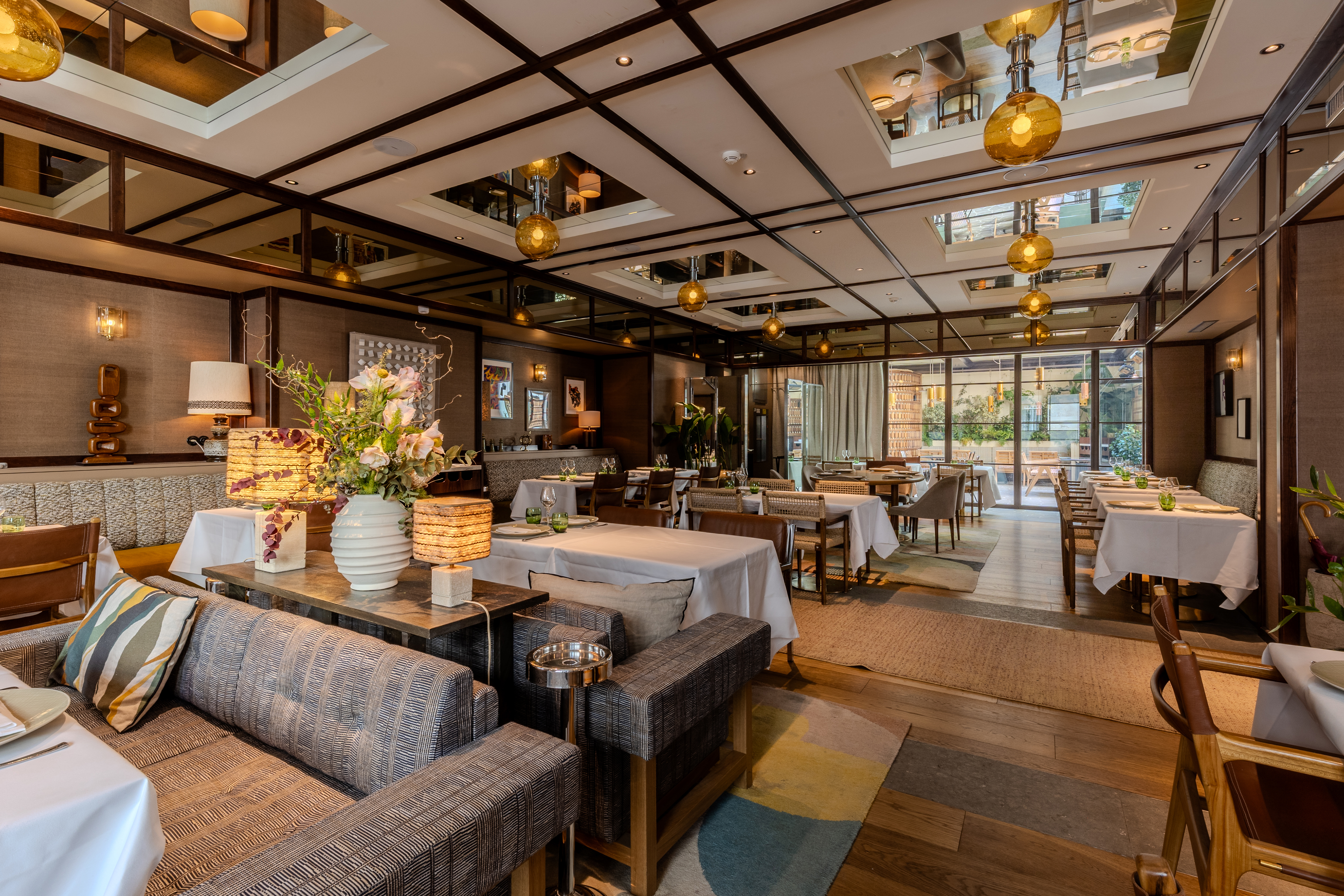 Hotel Norman restaurant, with sleek decor, wooden chairs, white clothed tables, and sofas, and arty light fittings