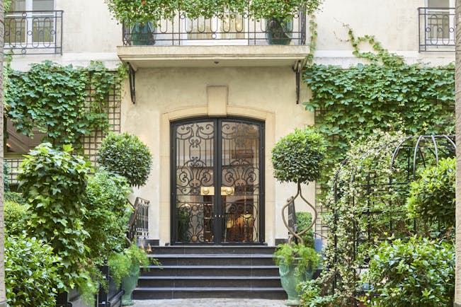 Entrnance to hotel with vines growing up hotel building and steps leading up to entrance