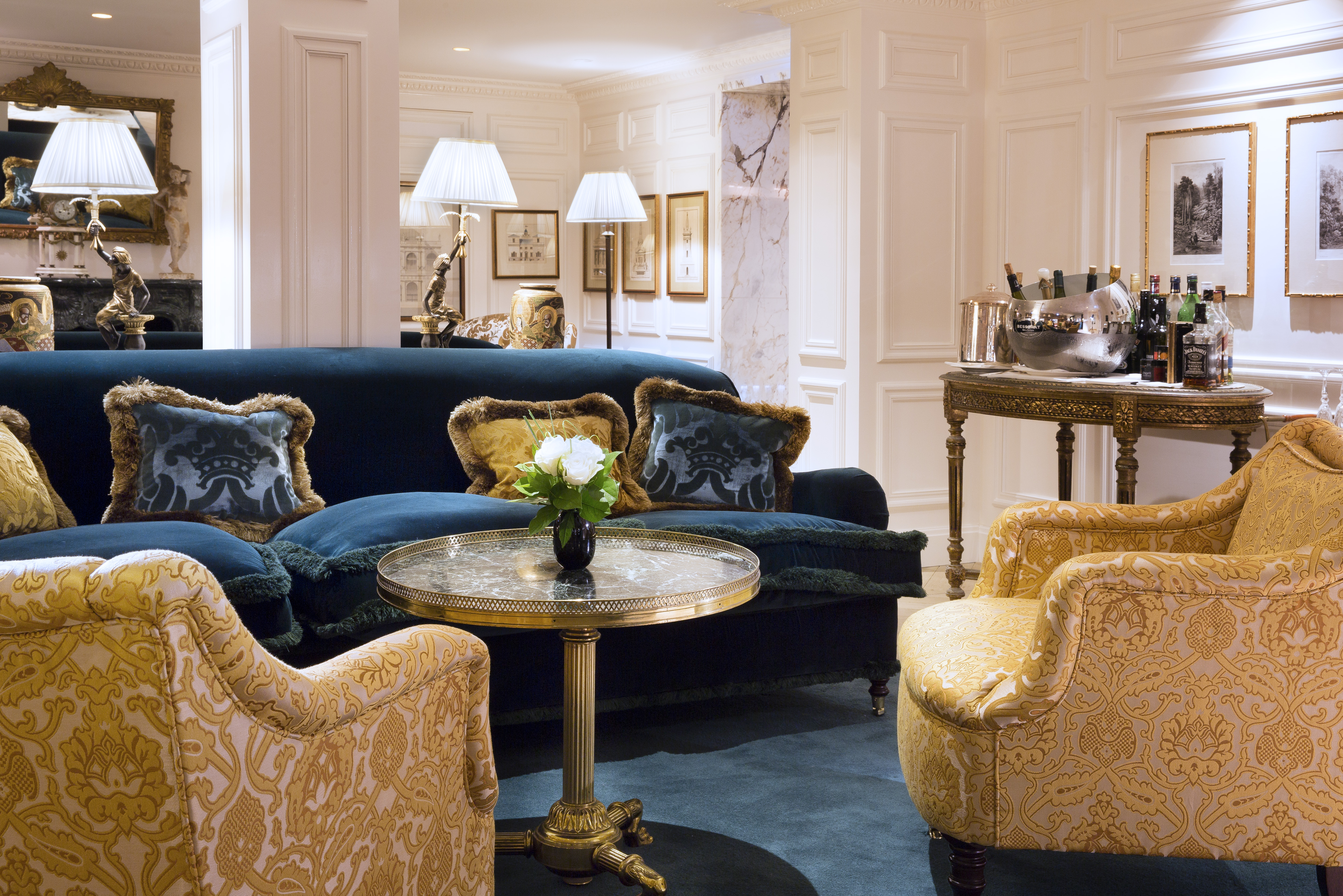 White lounge with blue and golden velvet seating areas 