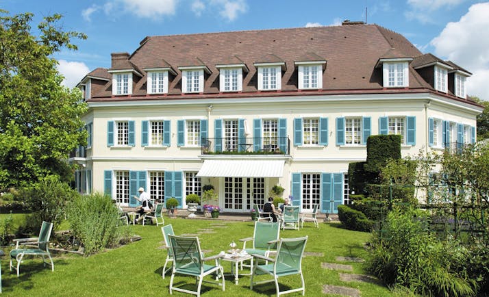 Chateau de Montreuil Pas de Calais exterior garden with table and chairs outside white building with blue shutters