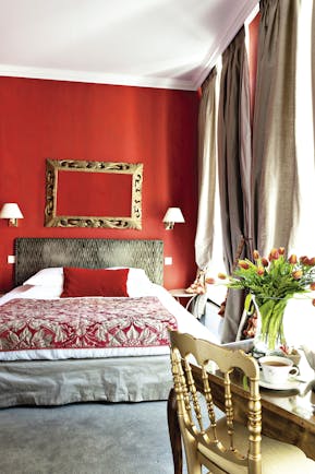 Double room at the Hotel de l'Univers with red painted walls a double bed and desk 