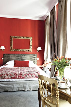 Double room at the Hotel de l'Univers with red painted walls a double bed and desk 