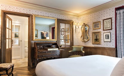 La Bastide de Gordes Provence deluxe bedroom with floral wallpaper and a large wooden writing bureau