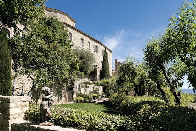 La Bastide de Gordes Provence exterior sculpture stone building garden trees and a sculpture of a young boy with grapes