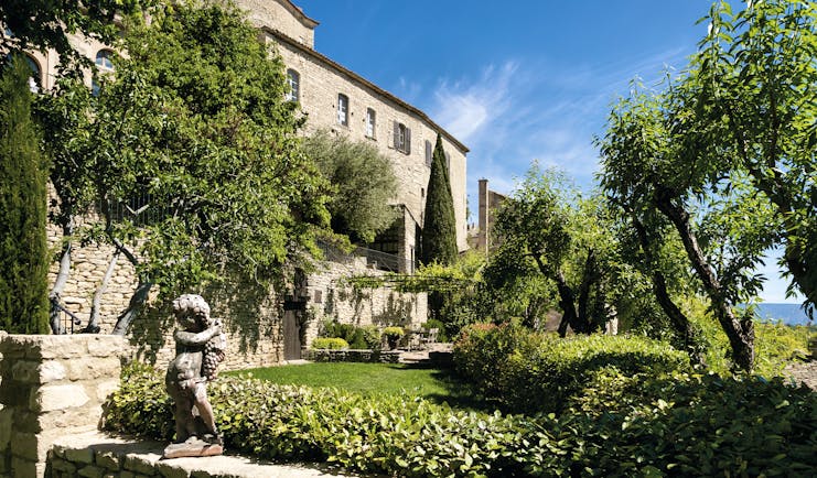 La Bastide de Gordes Provence exterior sculpture stone building garden trees and a sculpture of a young boy with grapes