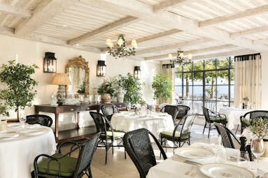 La Bastide de Gordes Provence Restaurant Orangerie dining area with chandeliers black wicker chairs and foliage