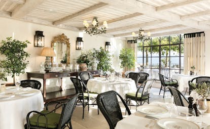 La Bastide de Gordes Provence Restaurant Orangerie dining area with chandeliers black wicker chairs and foliage