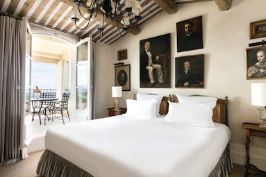 La Bastide de Gordes Provence suite duc bedroom several paintings of a man and a balcony seating area